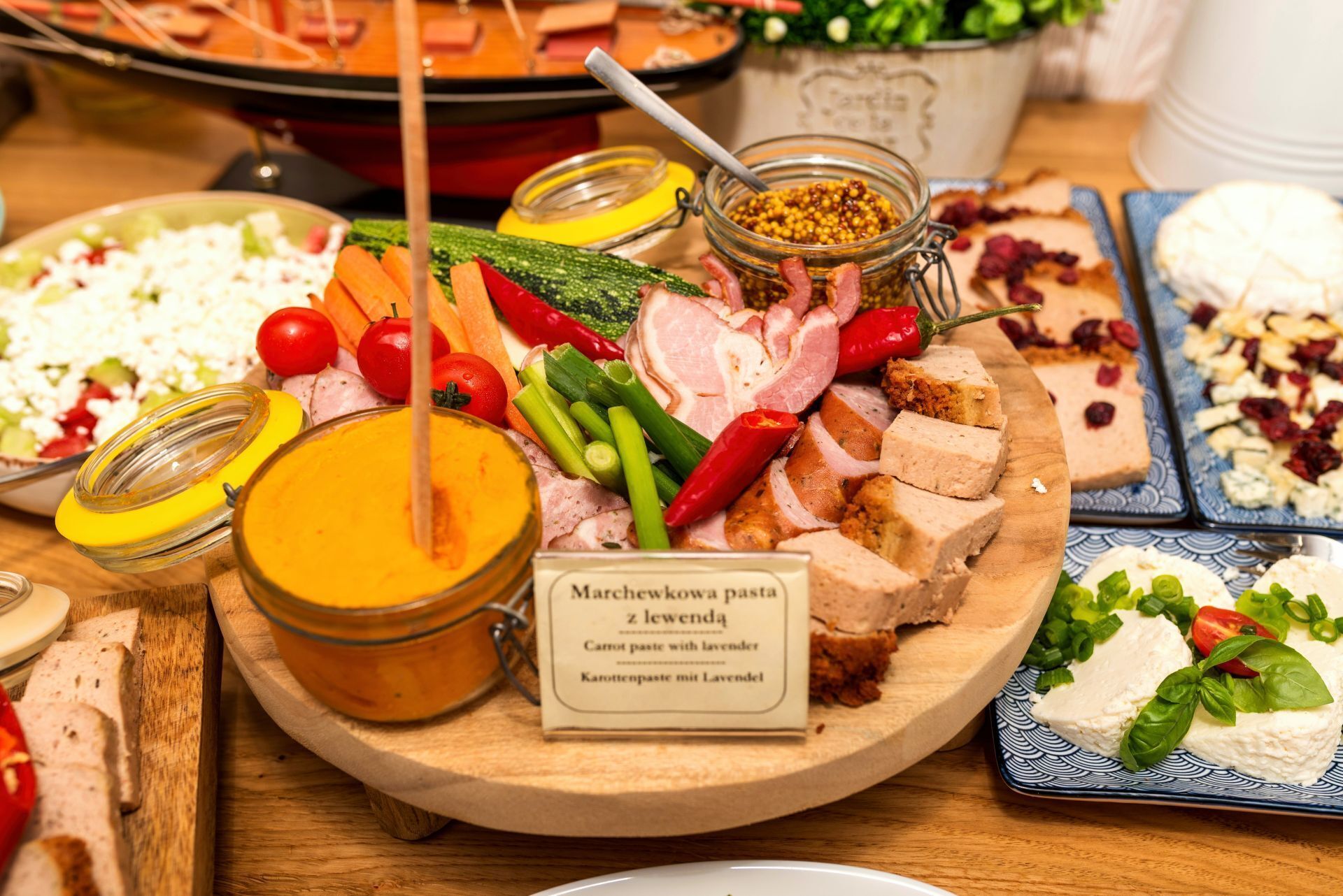 A variety of food items including cheese, vegetables, and meats on a wooden board.