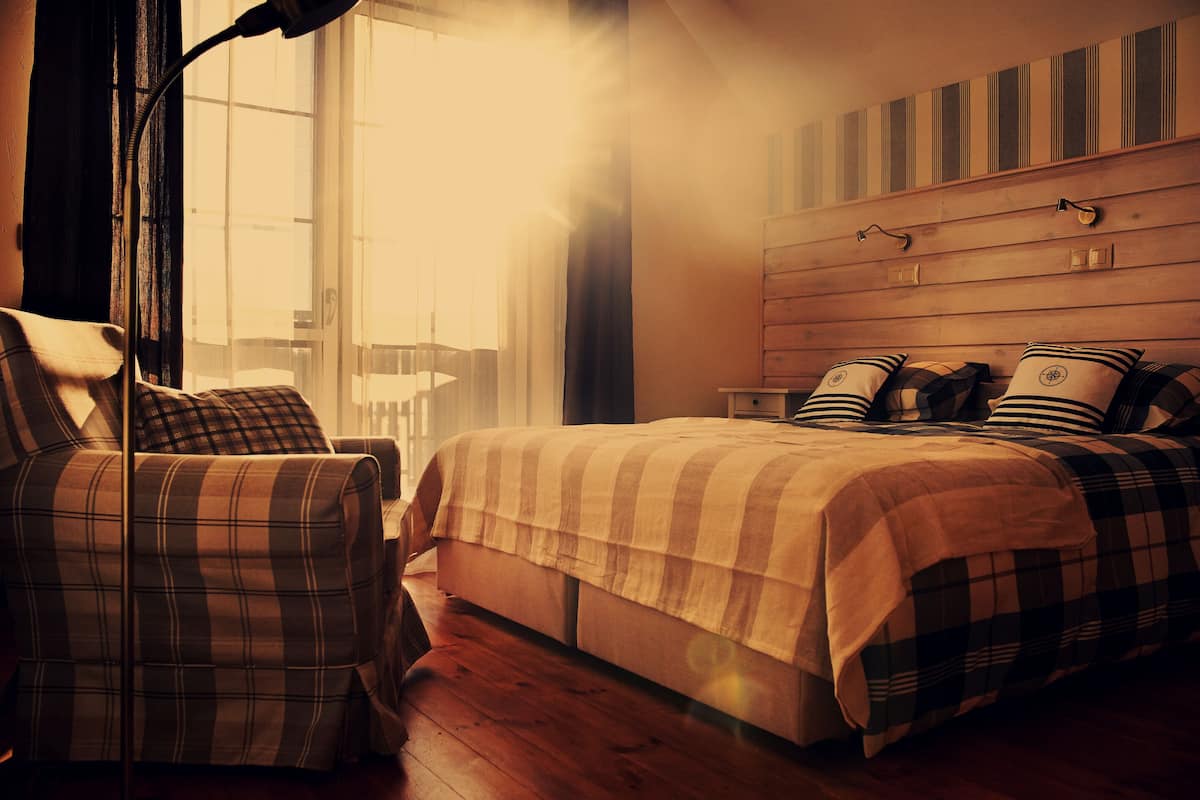 A bedroom with a bed, a chair, and a window with curtains.