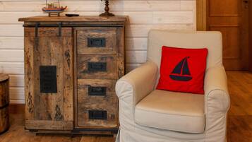 A room with a wooden cabinet, a television mounted on the wall, and a chair with a red pillow.