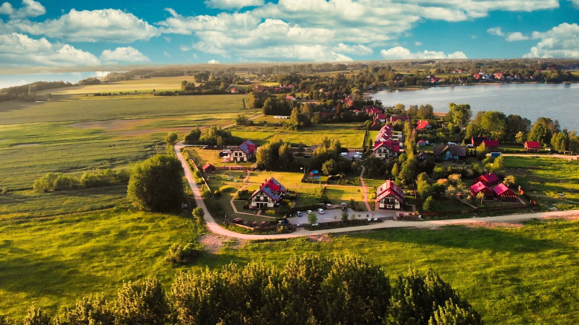 A rural village with traditional houses, a lake, and expansive fields.