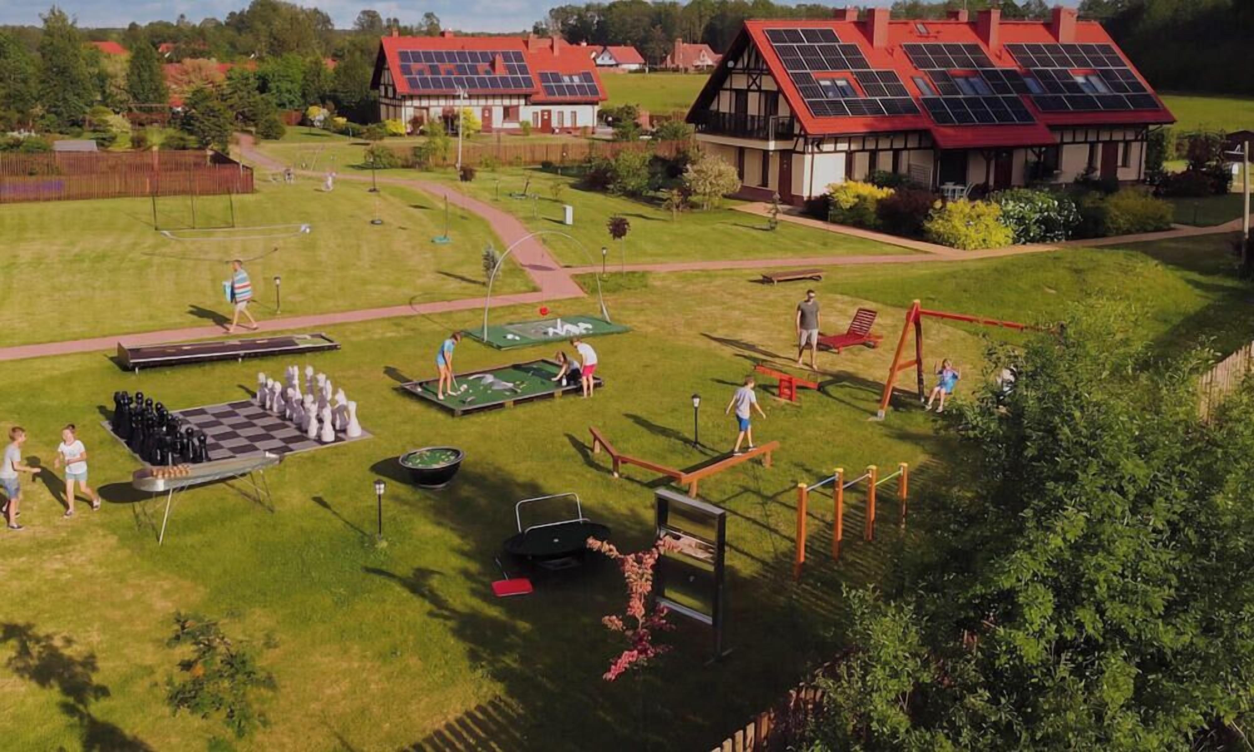 A grassy outdoor area with a chessboard, a swing set, and a small pool.