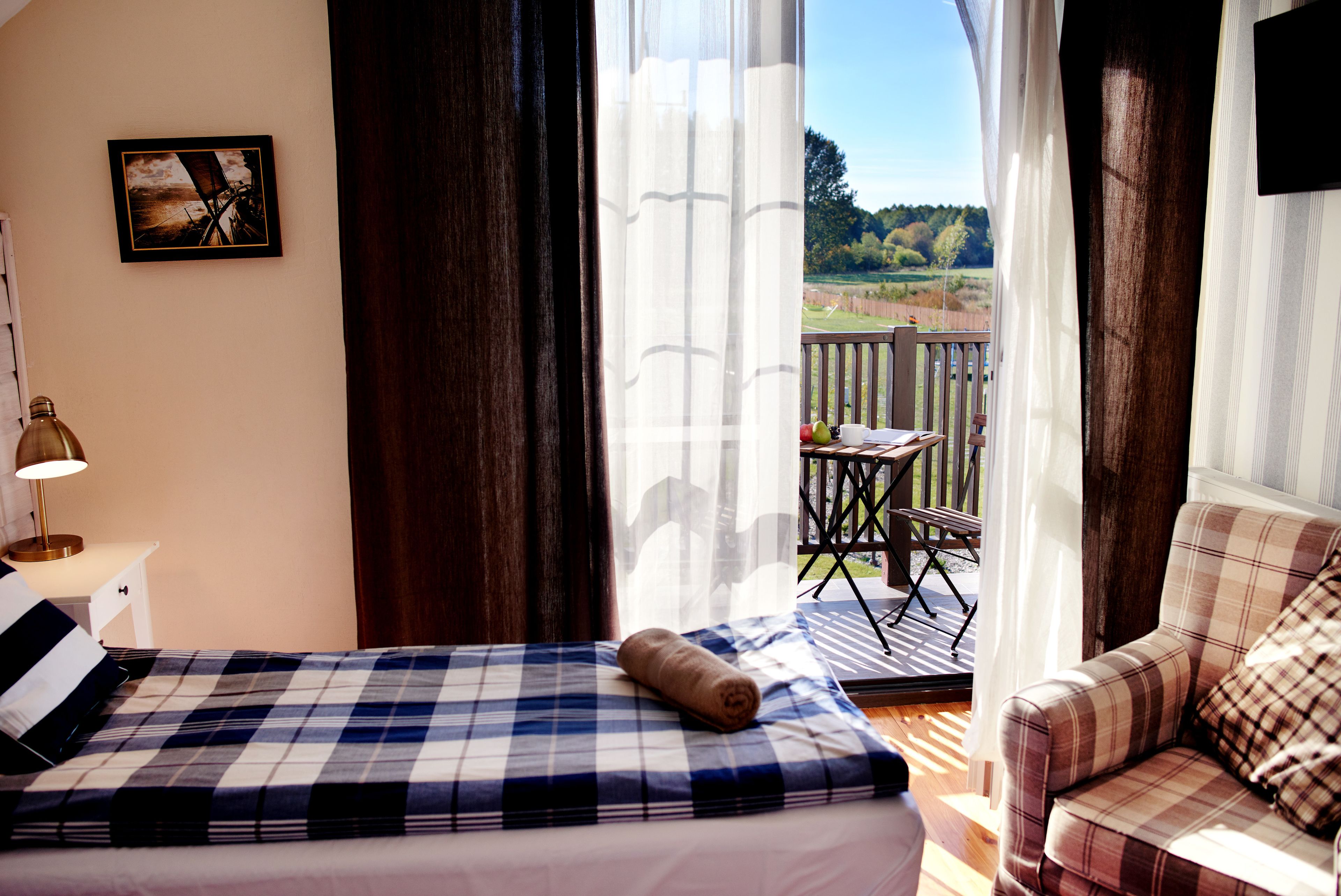 A bedroom with a bed, a chair, a table, and a view of the outdoors.