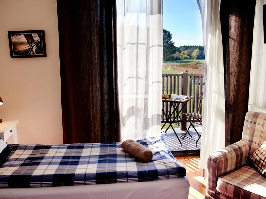 Un dormitorio con cama, una silla, una mesa y vistas al exterior.
