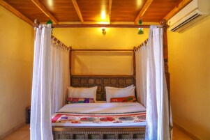 Una cama con dosel, un cabecero de madera y una colcha estampada.