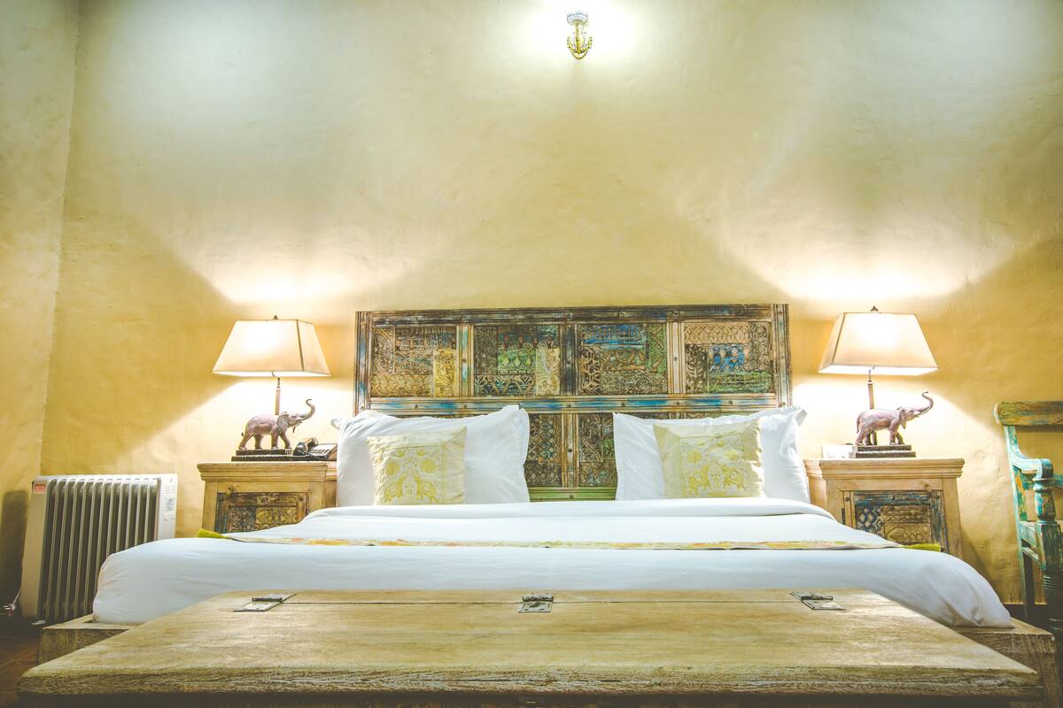 A hotel room with a large bed, two bedside lamps, and a decorative headboard.