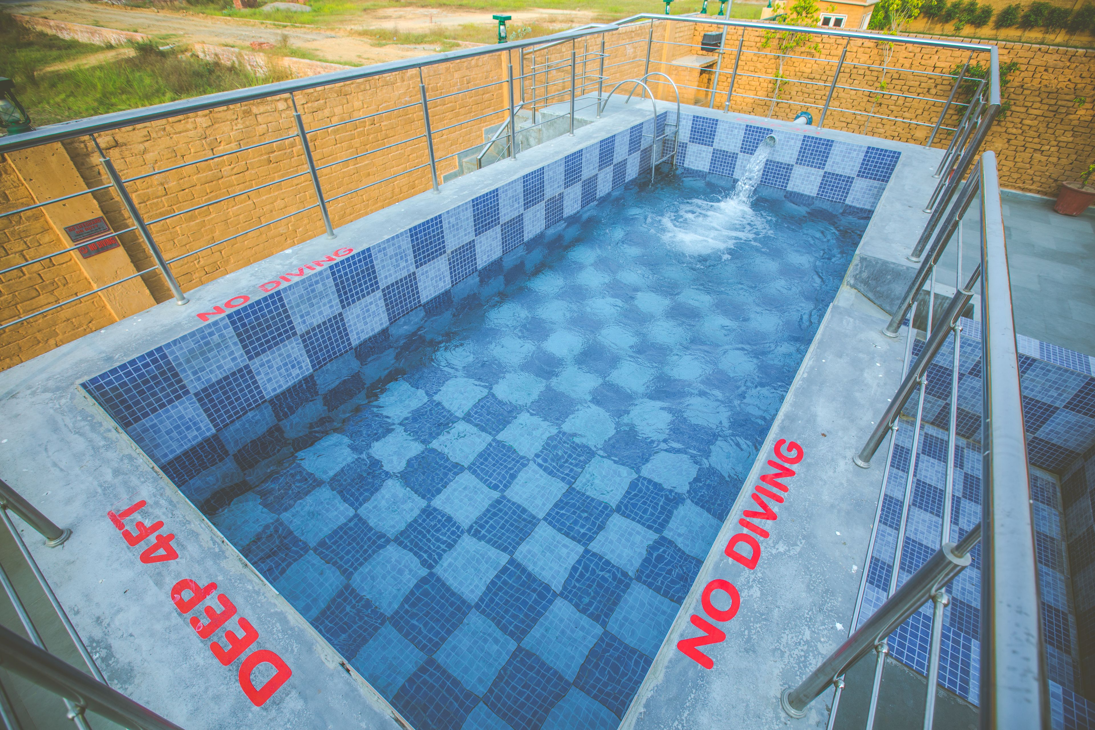 A swimming pool with blue and white checkered tiles and a metal safety railing.