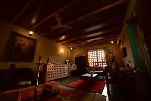 Un salón tradicional con vigas de madera, un ventanal grande, un sofá, una mesa de centro y un aparador.