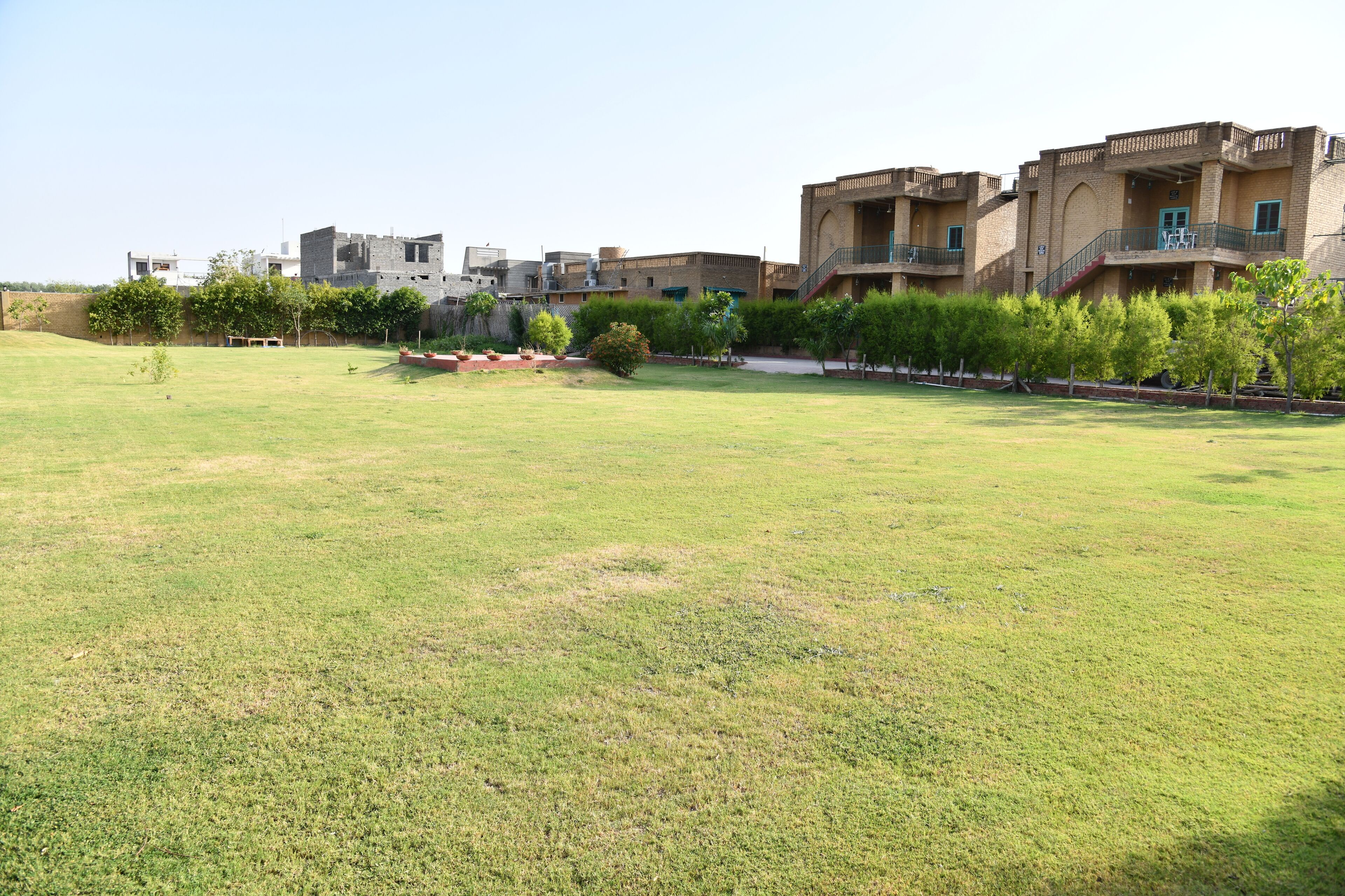 A large grassy area with a row of multi-story buildings in the background.