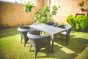 A patio with wicker furniture and a brick wall. - Welcomheritage Ranjit Vilas (Amritsar)