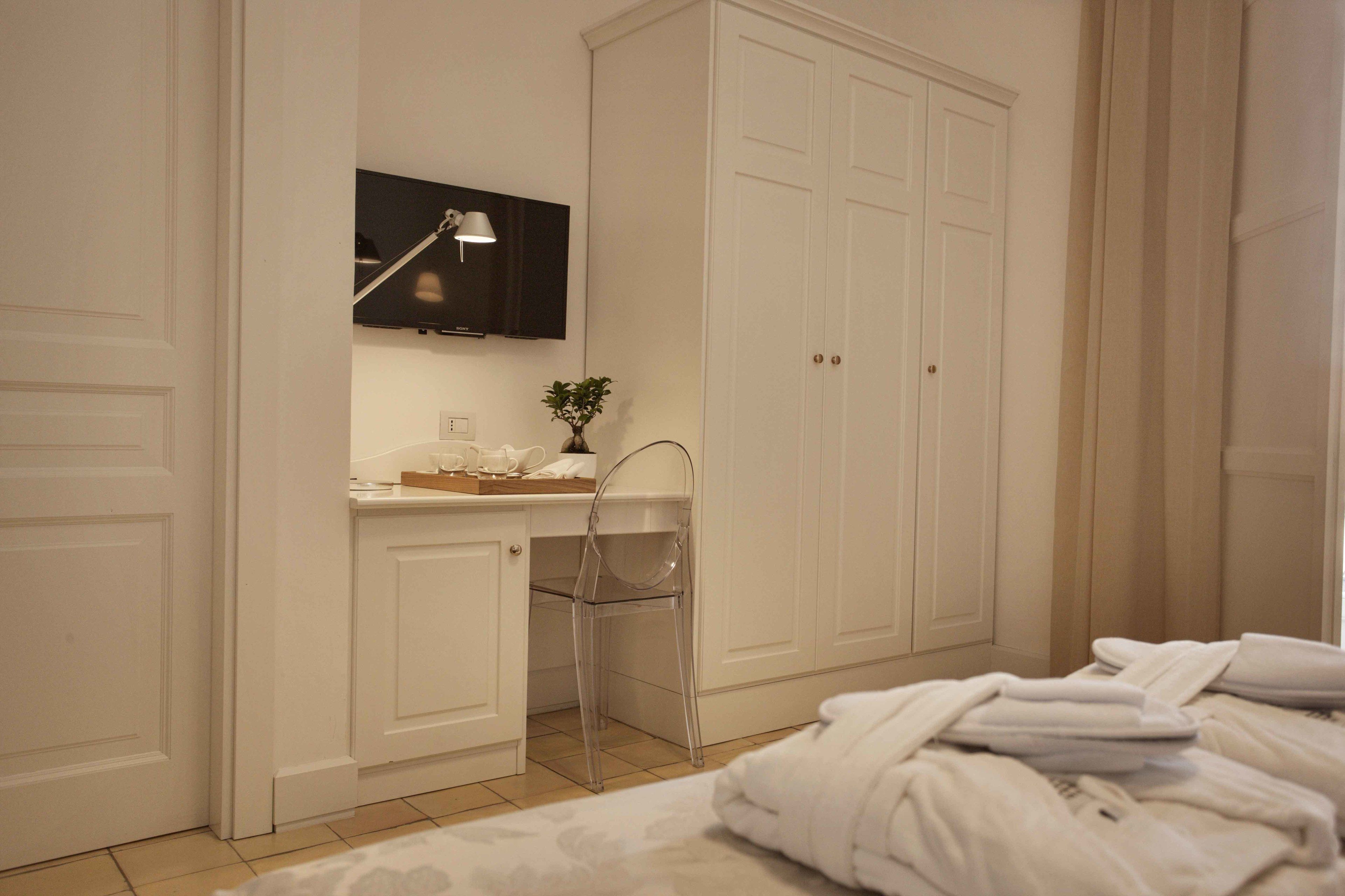 Un dormitorio con cama, escritorio con silla, televisor sobre el escritorio y armario.