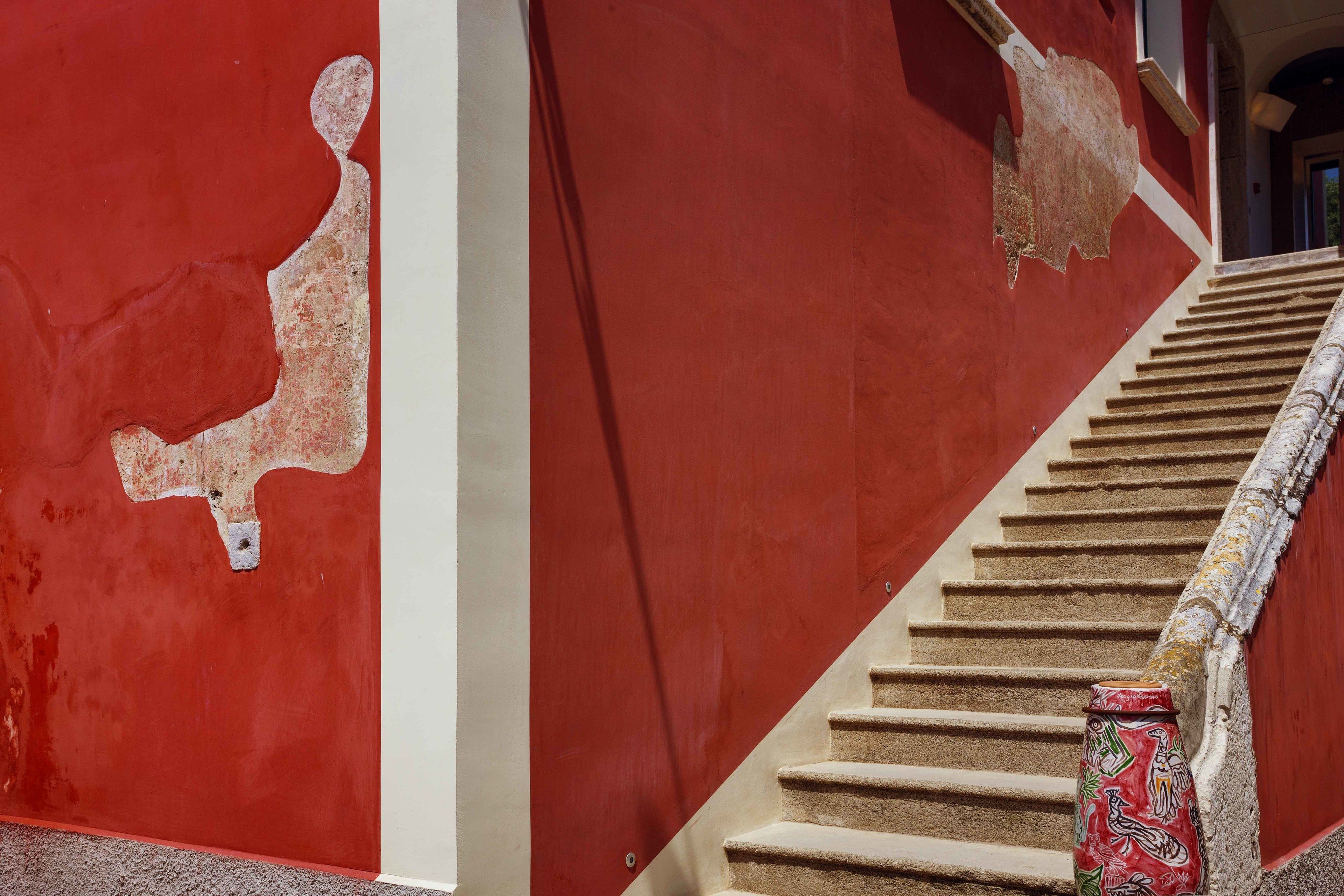 Una escalera con paredes rojas y una columna decorativa.