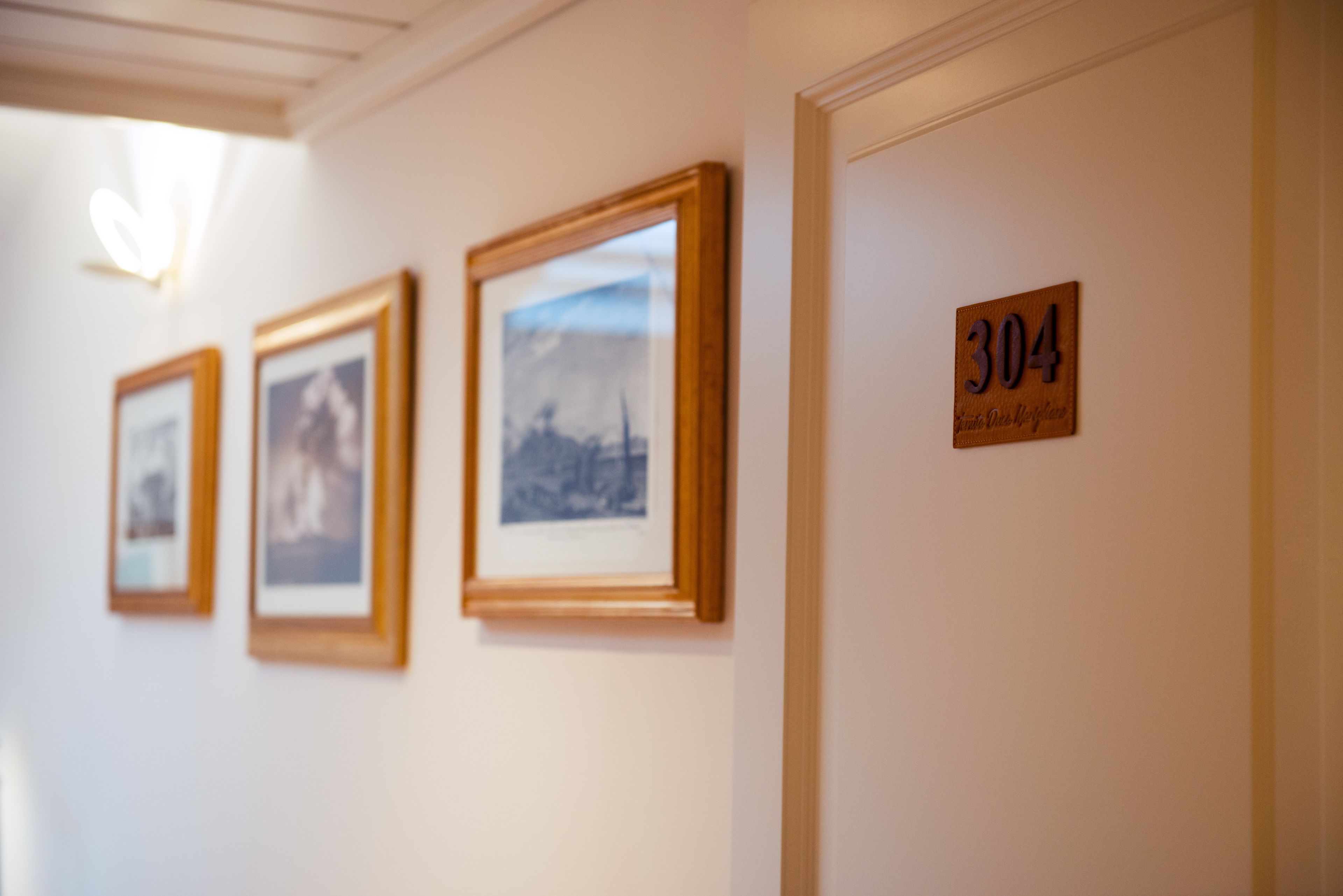 Ein Flur mit gerahmten Bildern an der Wand und einer Tür mit der Nummer 304.