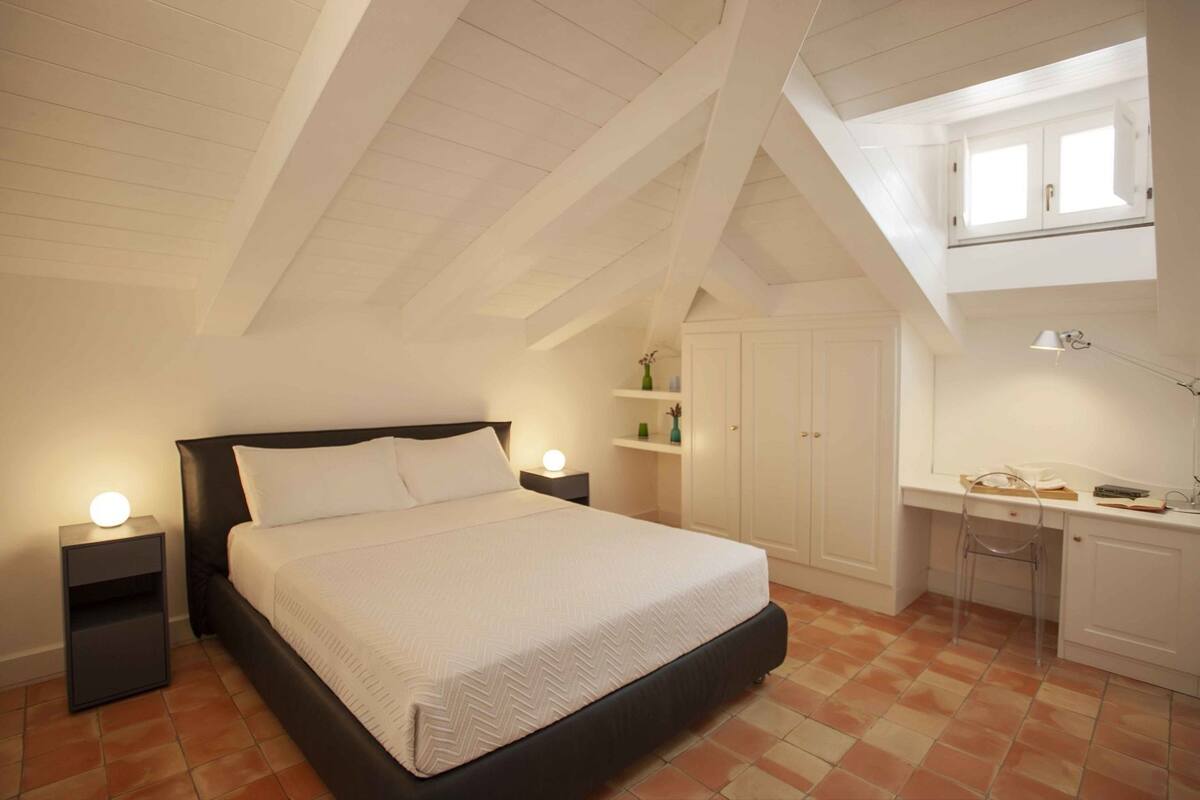Une chambre à coucher avec un lit, des tables de chevet, un bureau et une chaise.