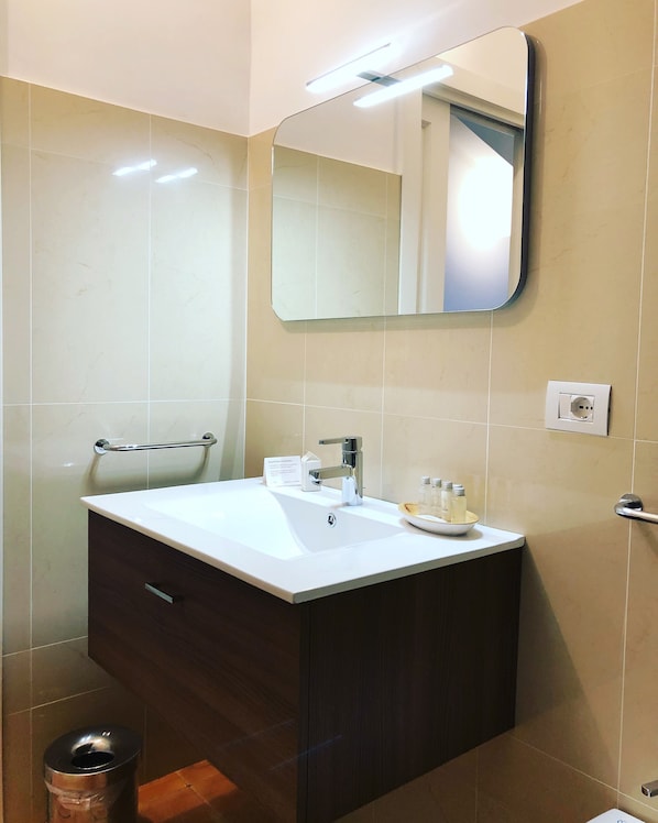 A bathroom with a white sink, dark wooden cabinet, and a mirror above it. - Tenuta Duca Marigliano Boutique Hotel (Capaccio-Paestum)