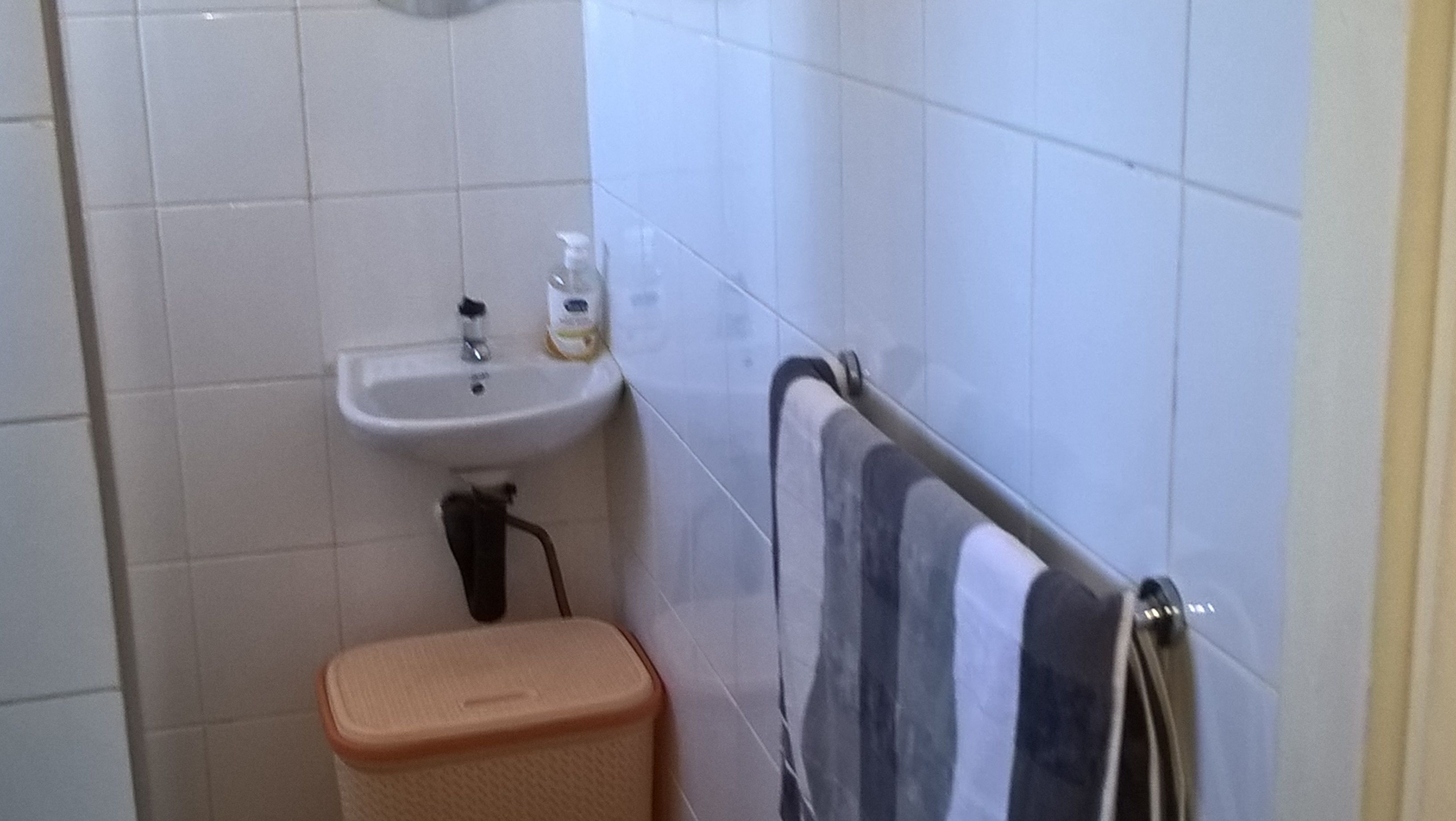 Une petite salle de bain avec un lavabo blanc, un porte-serviettes et une poubelle.