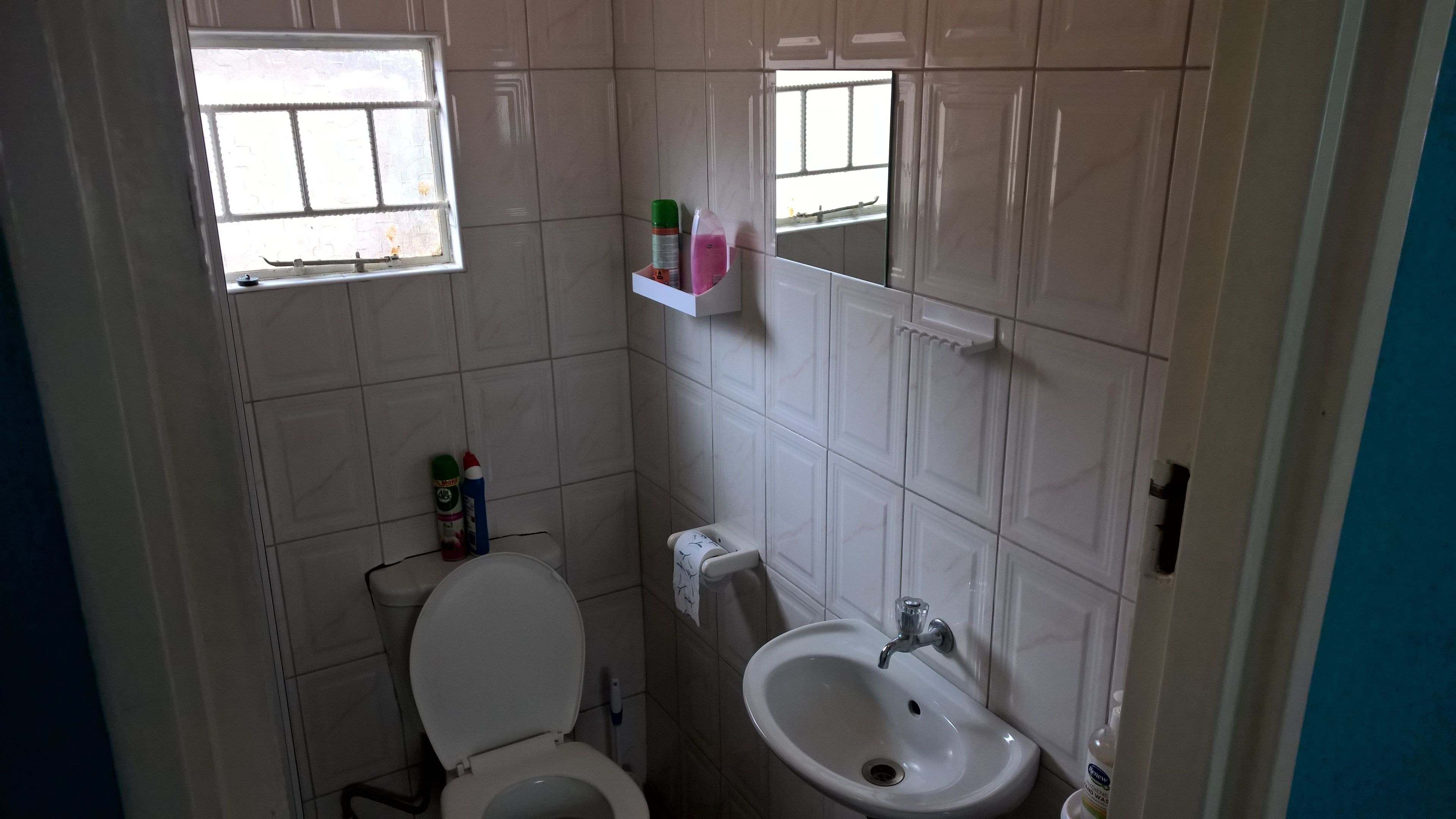 A small bathroom with a toilet, sink, and window.