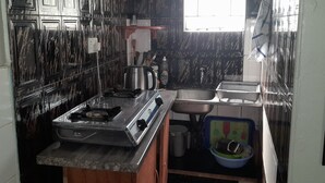 A compact kitchen with a gas stove, a sink, and a window providing natural light. - Mambilima Furnished Guest Wing (Lusaka)