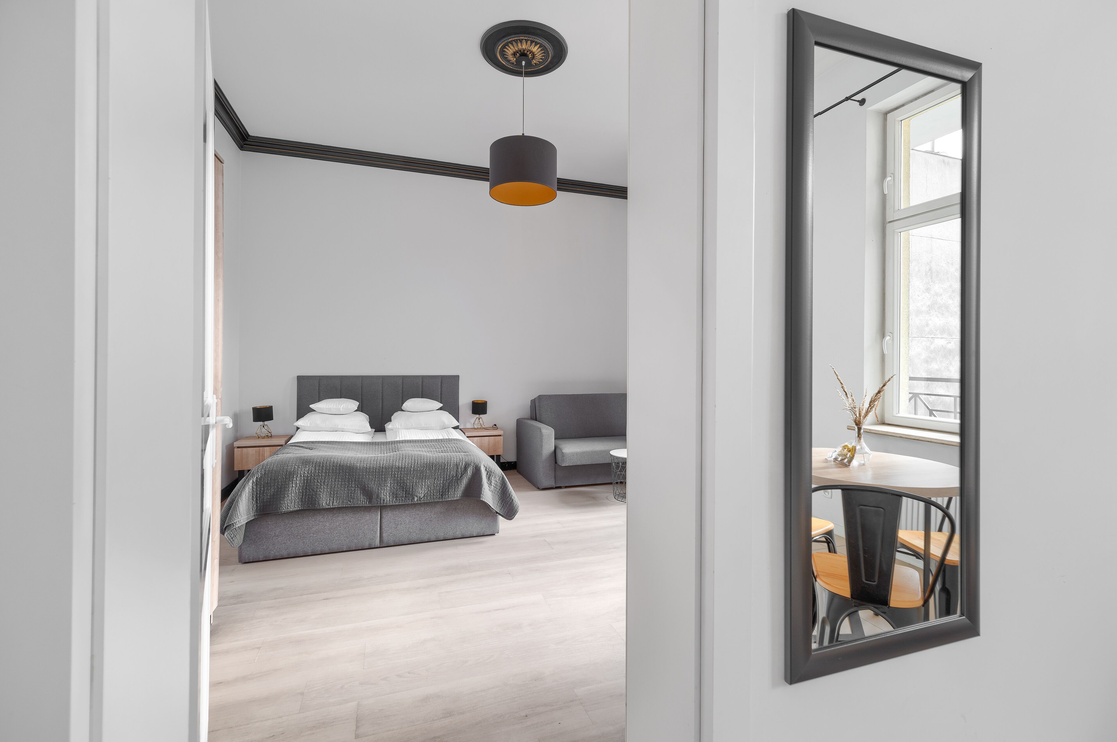 A modern bedroom with a bed, bedside tables, a desk, and a chair.