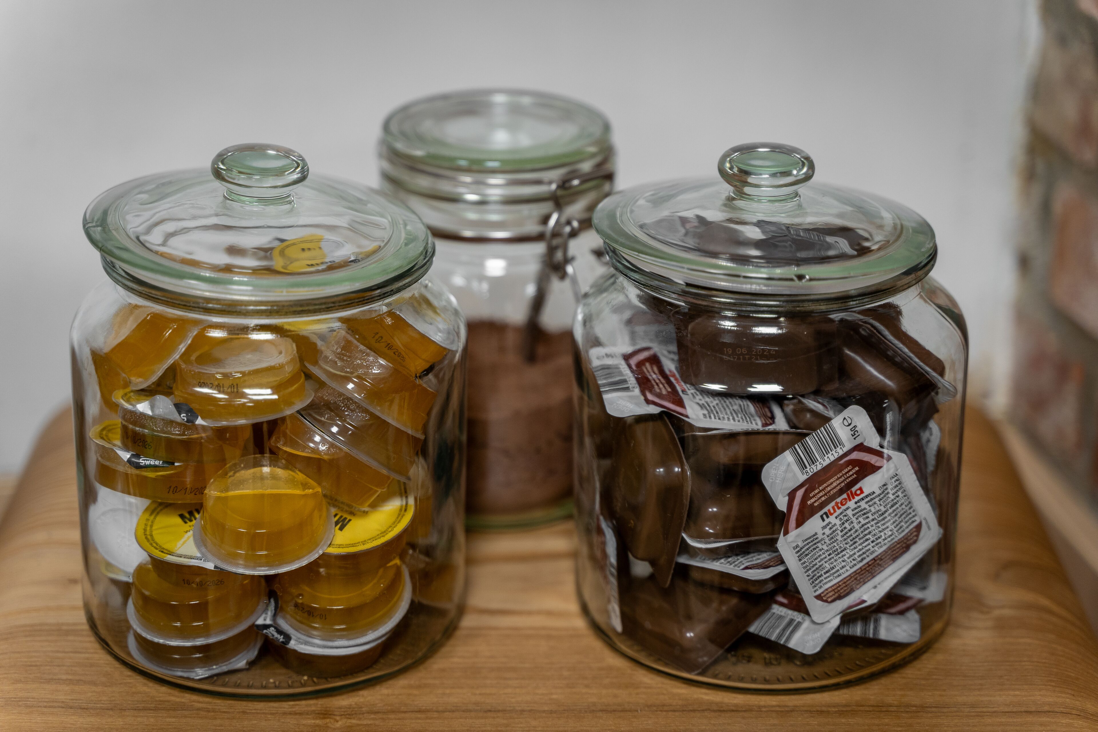 Two glass jars with metal lids on a wooden shelf.