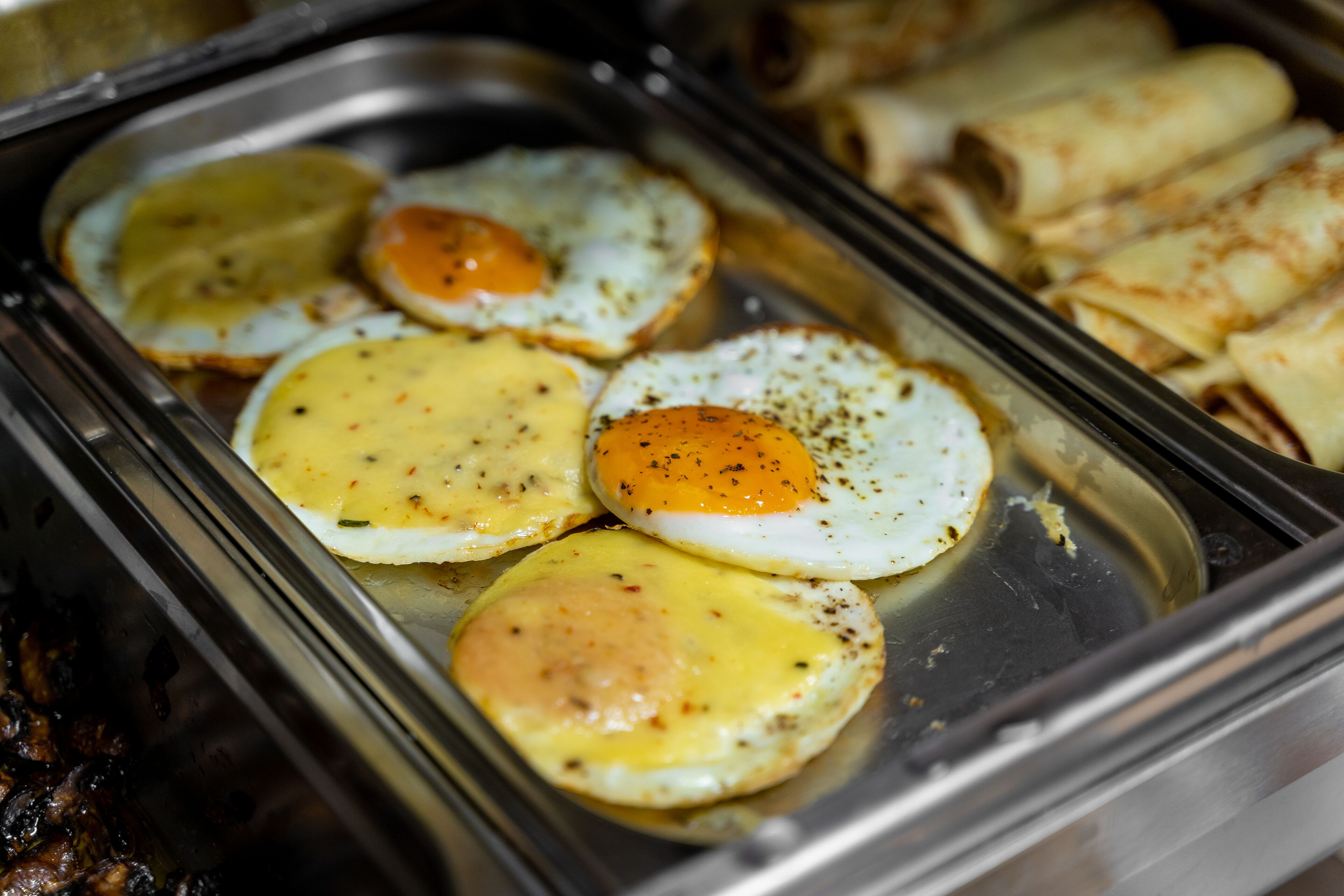 Een buffet met warme eieren en rolletjes gebak.