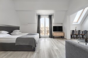 Una habitación de hotel moderna con una cama grande, un televisor, un escritorio y una zona de comedor.