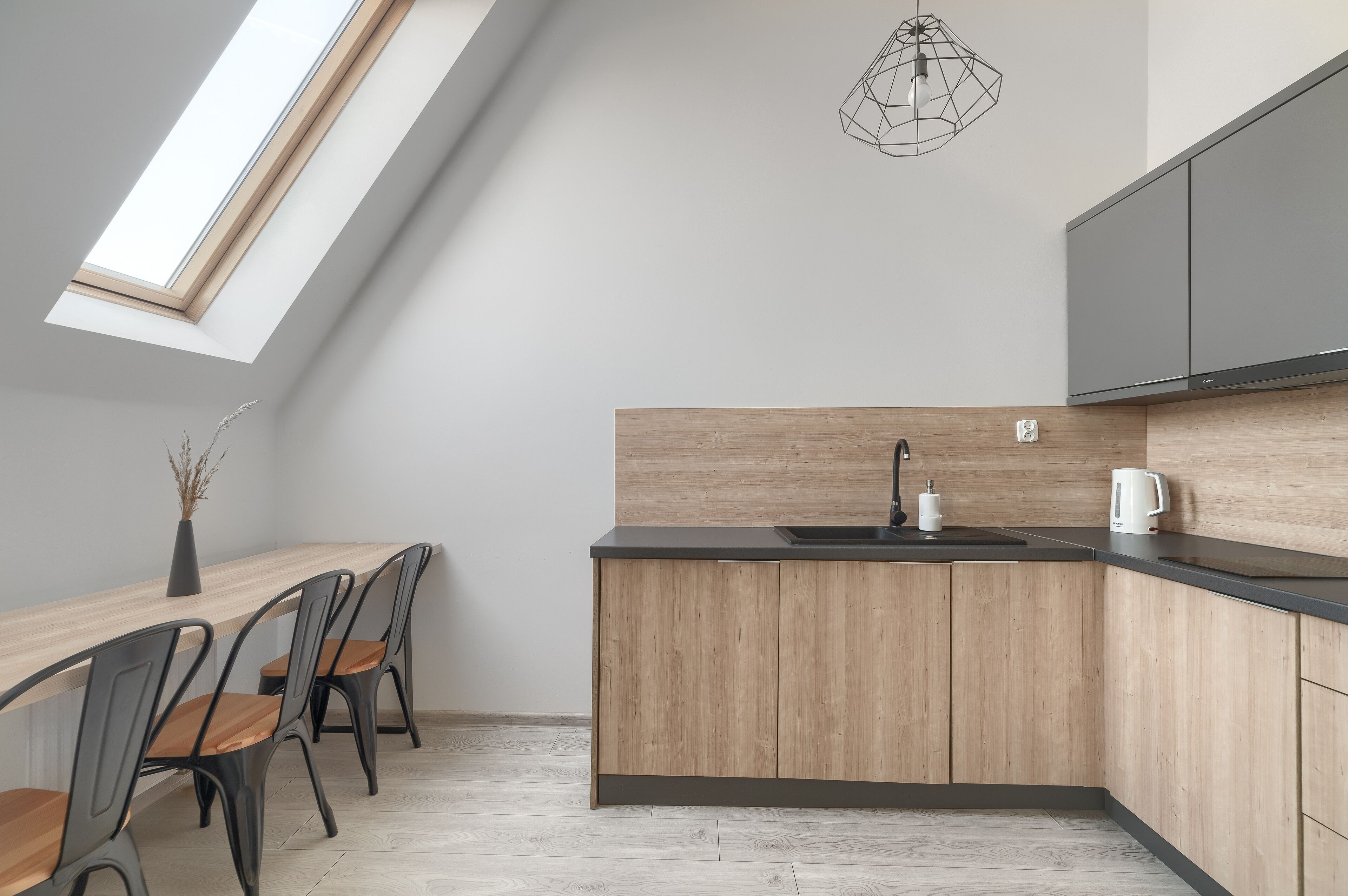 A modern kitchen with a skylight, wooden cabinets, and a black countertop.