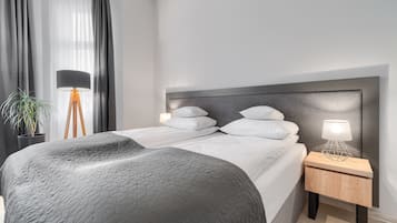 A modern bedroom with a large bed, a bedside lamp, and a potted plant.