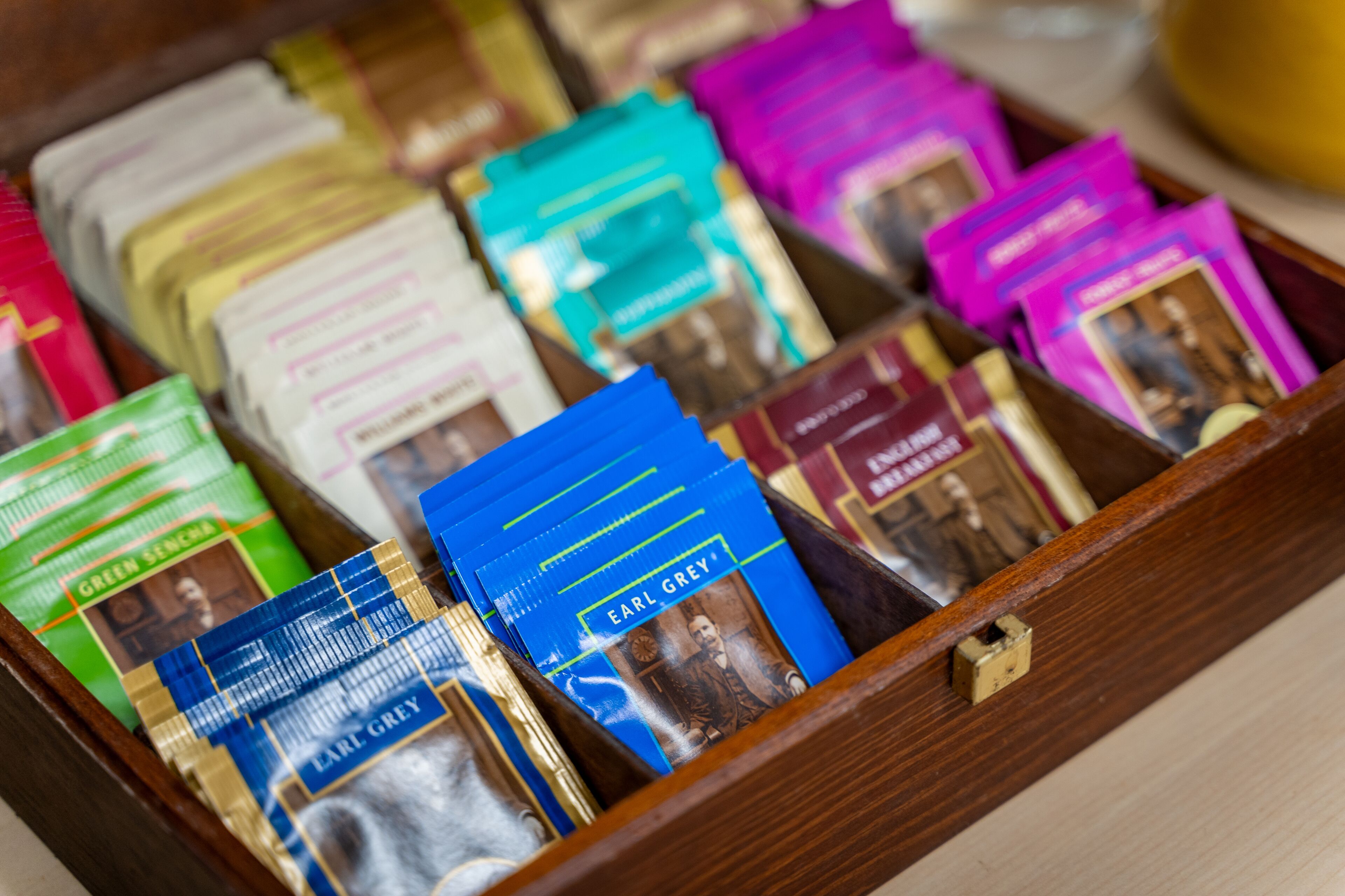 A wooden drawer containing various packets of tea, some labeled with names like Earl Grey.
