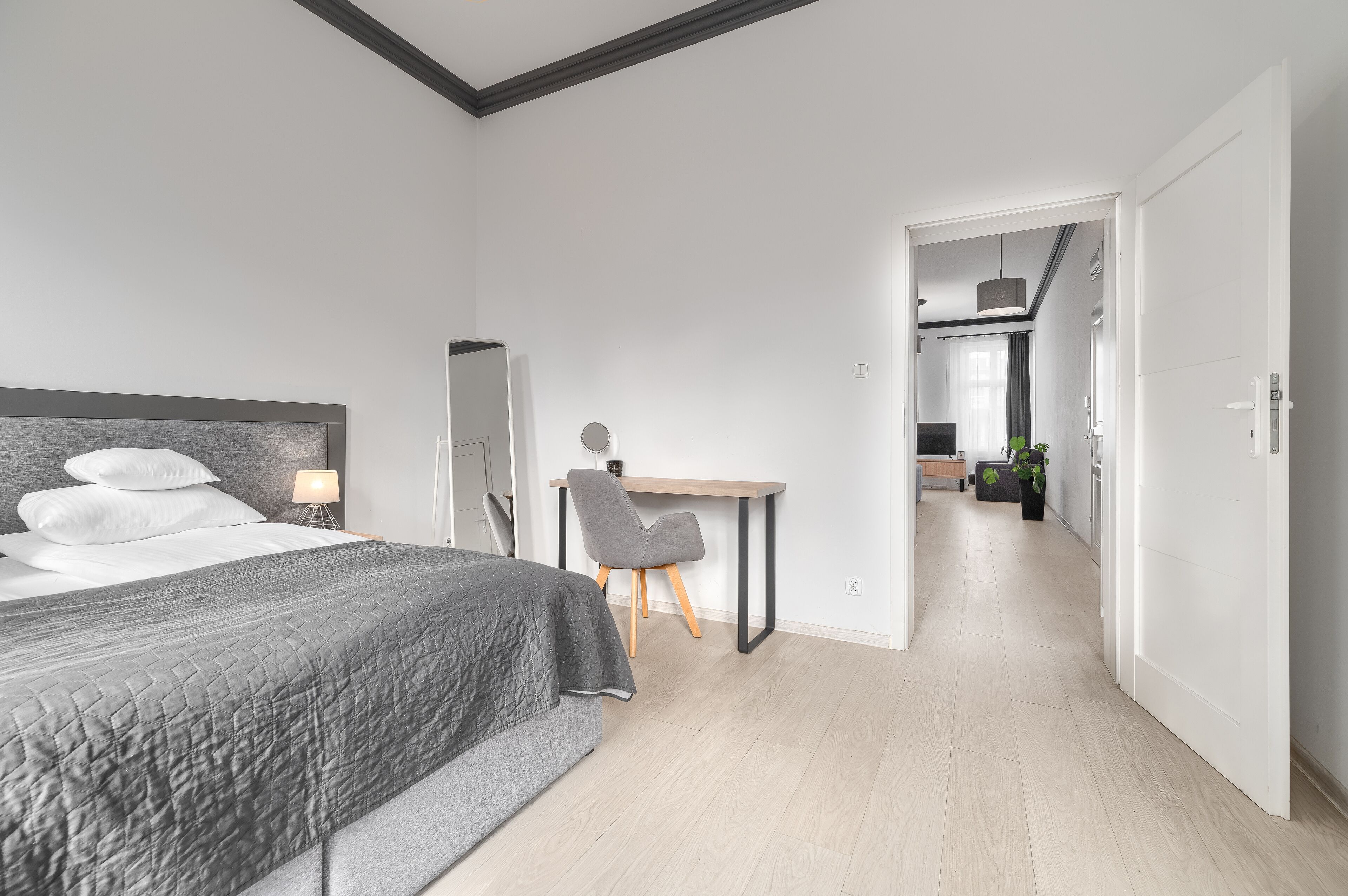 Ein modernes Schlafzimmer mit einem Bett, einem Nachttisch und einem Schreibtisch mit Stuhl.