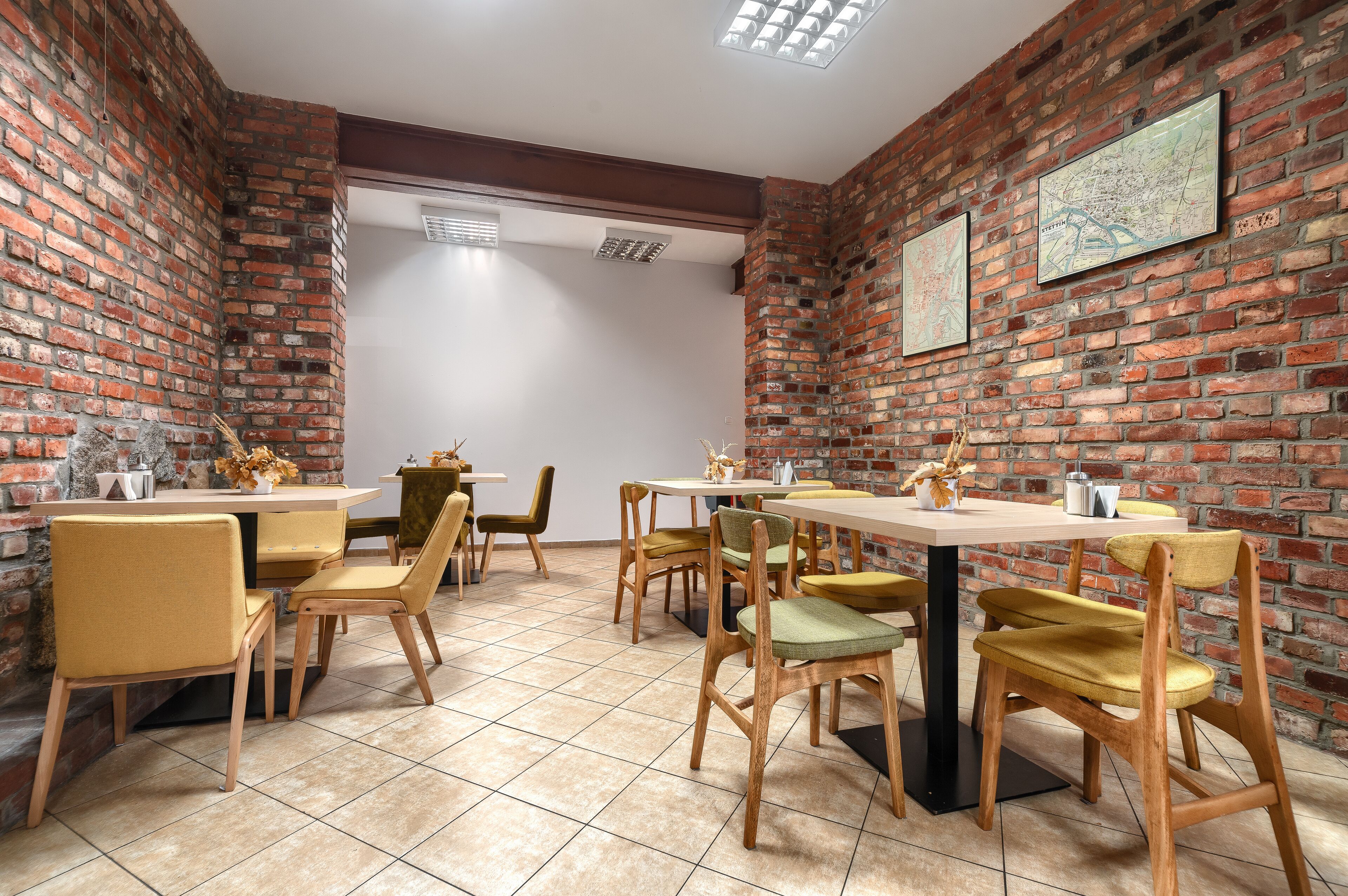 A dining area with brick walls, wooden tables, and yellow chairs.