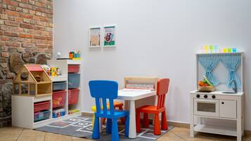 Una sala de juegos con pared de ladrillo, una casita de juegos y una cocina de juguete.