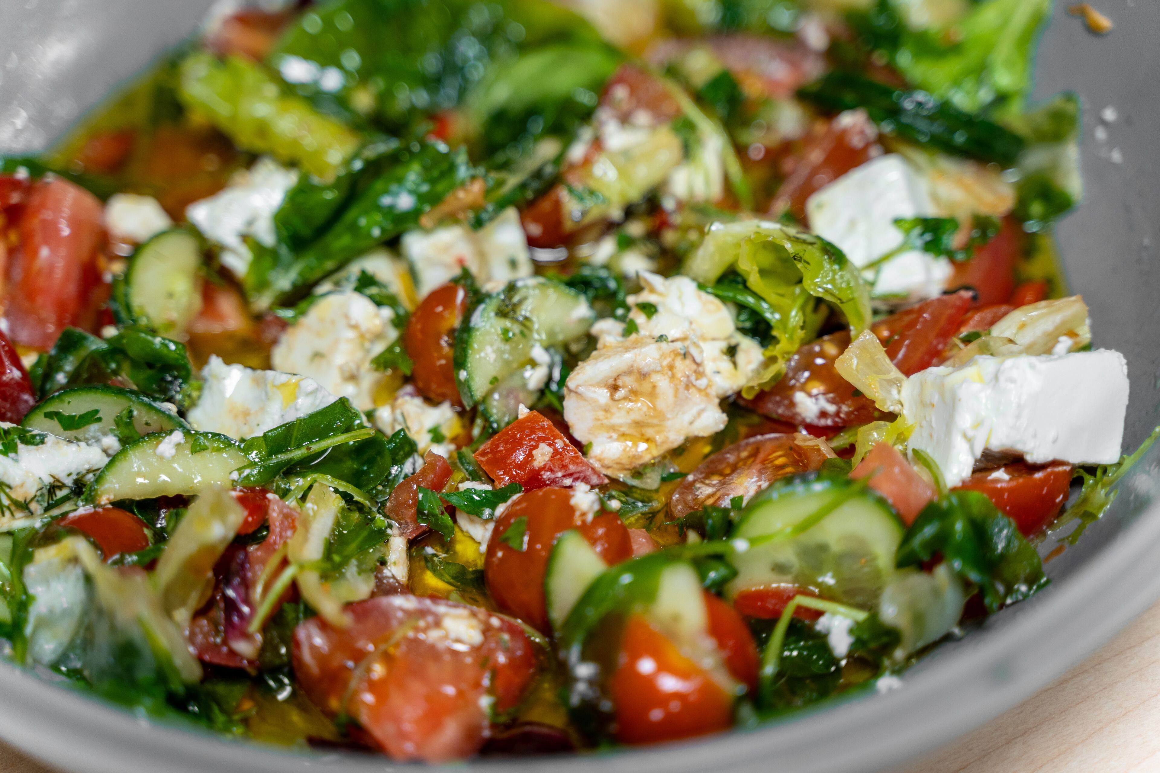 A bowl of salad with various vegetables and feta cheese.