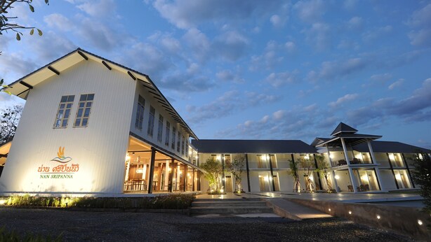 A modern hotel with a white facade, multiple windows, and a well-lit entrance. - Nansripanna Resort (Nan)