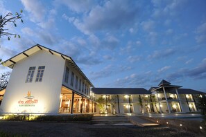 A modern hotel with a white facade, multiple windows, and a well-lit entrance. - Nansripanna Resort (Nan)
