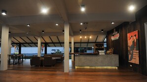 A spacious lobby with a reception desk, seating area, and large windows overlooking a parking area. - Nansripanna Resort (Nan)