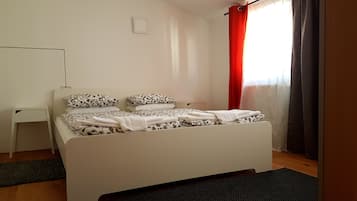 Un dormitorio con cama, escritorio y ventana con cortinas.