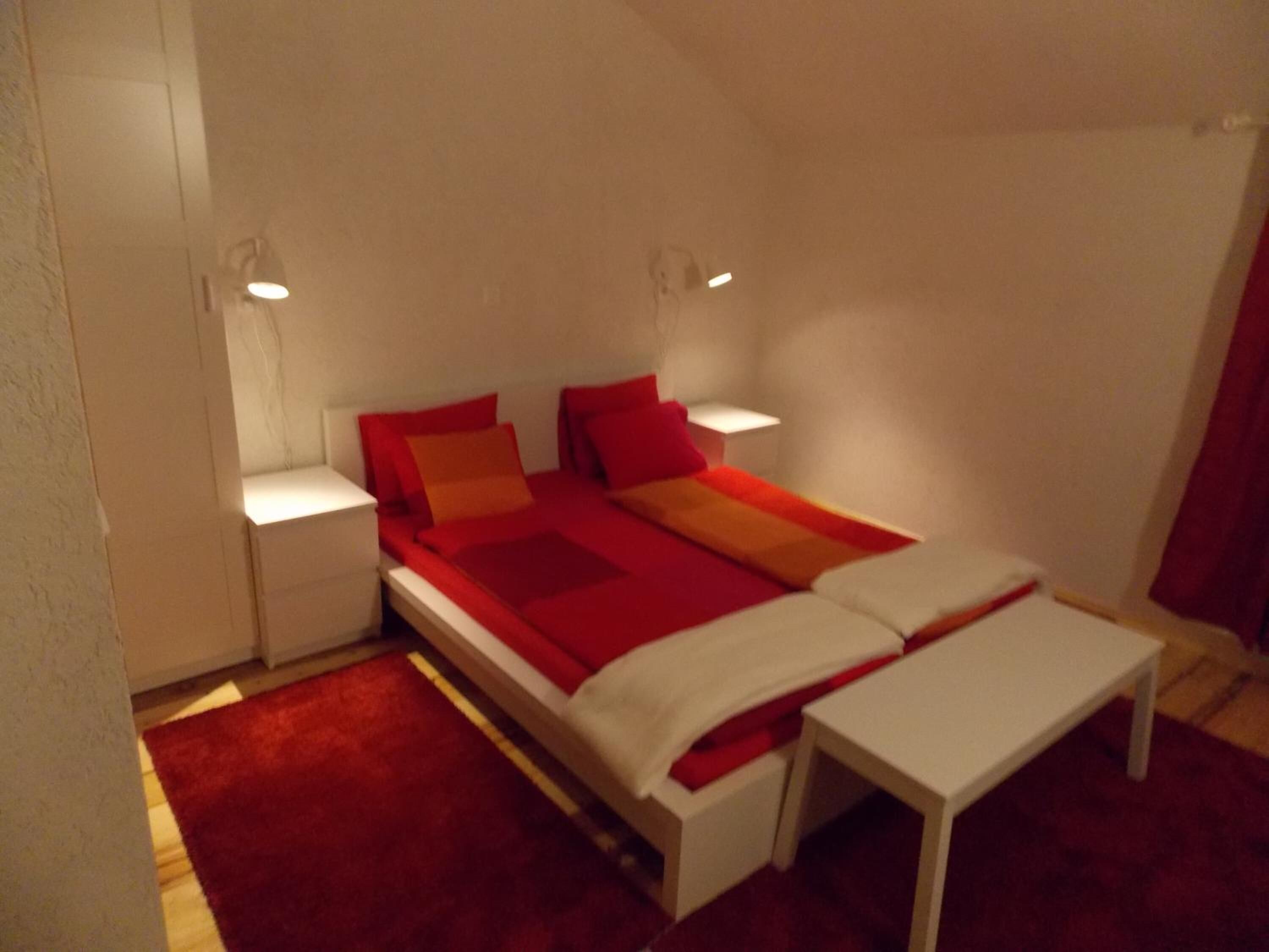 Un dormitorio con cama, mesitas de noche y velador.