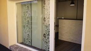 Une pièce dotée d’une porte-fenêtre coulissante ornée d’un motif décoratif, d’un socle en pierre et d’un plancher foncé.