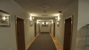 Un couloir d’hôtel avec un plancher en bois, des tableaux encadrés accrochés aux murs et un tapis.