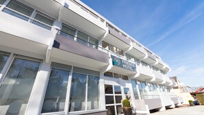 Un hôtel au concept « entre amis », doté d’une architecture moderne, de grandes fenêtres et offrant une vue sur un ciel dégagé.