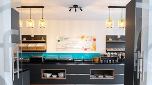 Un hall d’hôtel moderne avec un comptoir d’accueil, des portes vitrées et un espace buffet.