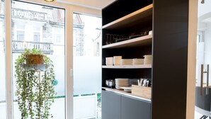 Une cuisine moderne avec un meuble intégré noir, un plancher en bois et une plante suspendue.