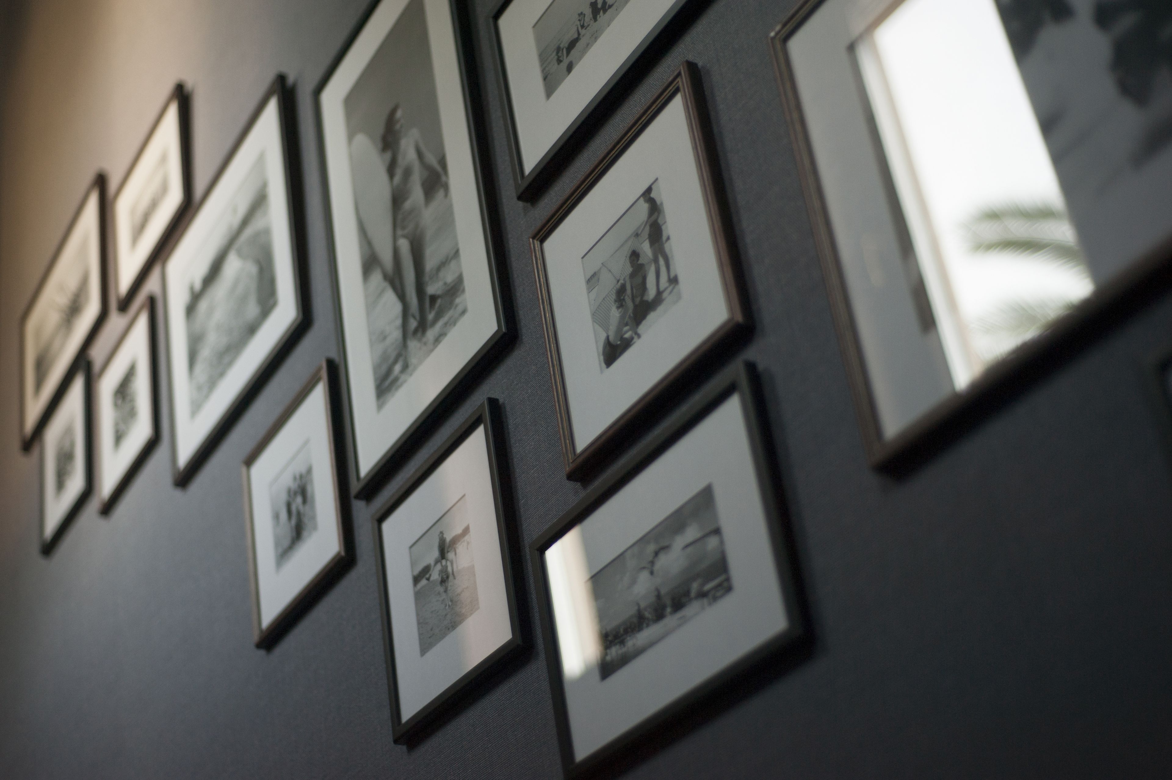 Eine Wand mit mehreren in Bilderrahmen gefassten Fotografien, die in einem Raster angeordnet sind.