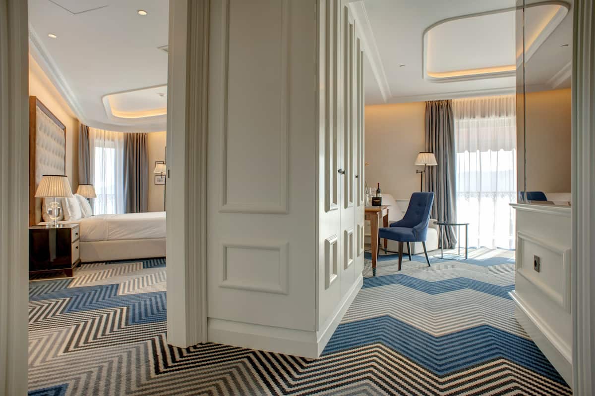 A hotel room with a bed, a desk, a chair, and a large mirror.