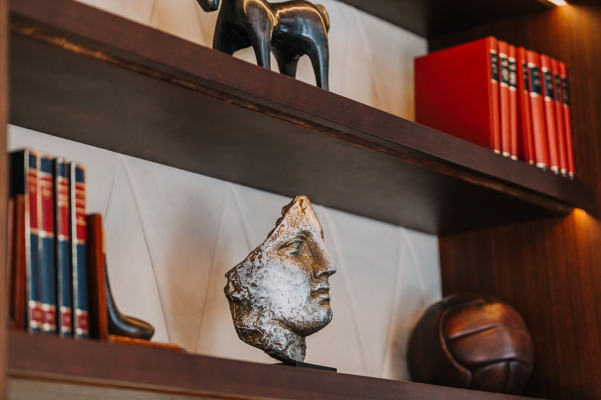 A bookshelf with books, a sculpture, and a basketball.