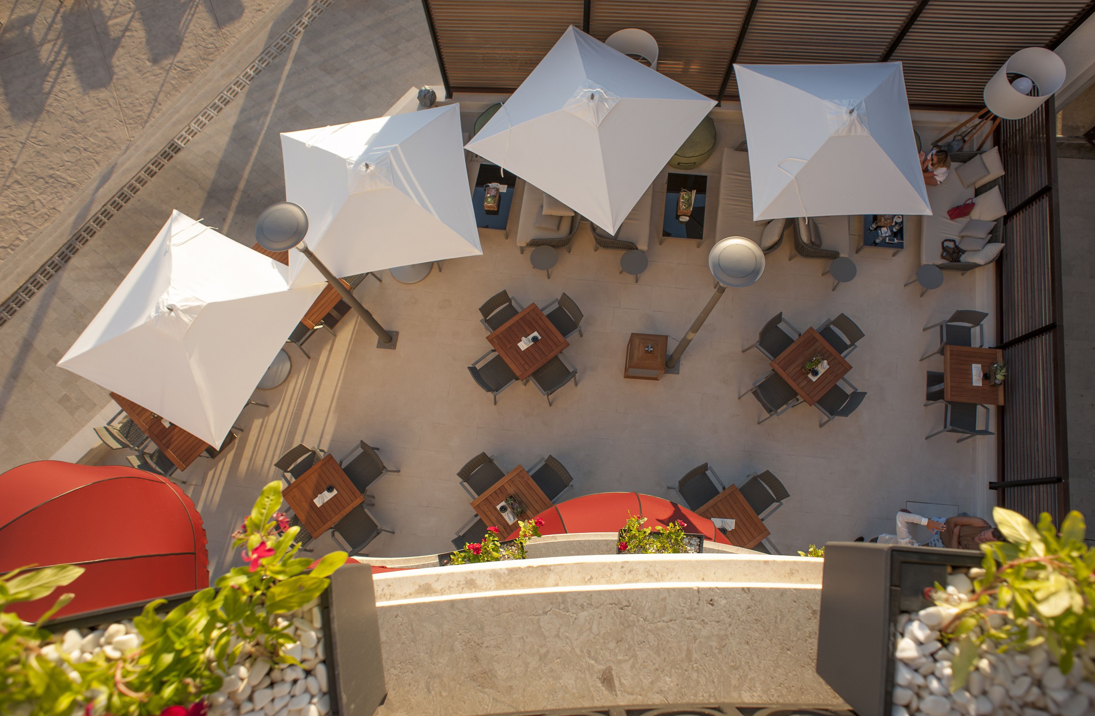 Un espace extérieur aménagé avec des tables, des chaises, des parasols et des plantes en pot.