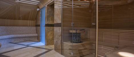 A modern spa area with a wooden ceiling, a glass partition, and a marble floor.