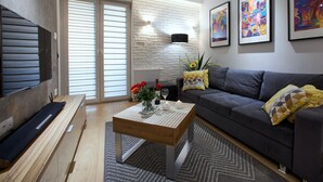A modern living room with a grey sofa, a wooden coffee table, and a TV mounted on the wall. - 4UApart - Apartment suite Picasso (Swinoujscie)
