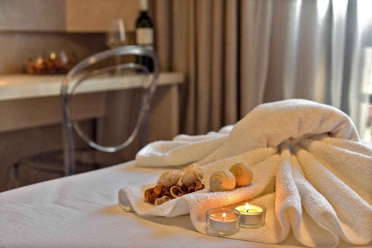 A neatly arranged towel with a candle and dried flowers on a bed, suggesting a relaxing setting.