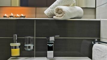 A modern bathroom with a bathtub, a towel rack, a soap dispenser, and a glass of water.